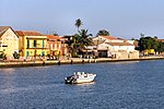 Waterfront with buildings and palm trees, a boat in water
