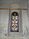 L'unique grand vitrail orné de décors végétaux et de fleurs : sur le médaillon est représentée la Vierge Marie avec l'Évangile.
