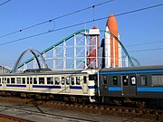 駅に到着する普通列車。背後は、スペースワールドのジェットコースター「ヴィーナスGP」（2005年9月）