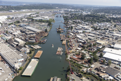 An aerial photo of the Duwamish waterway. Many barges are visible, and the river is surrounded by warehouses and other industrial buildings.