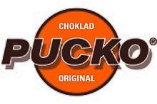Logo of Pucko. Dark brown upper case letters in san serif typeface with white borders and shadows on top of an orange filled circle with a border in the same dark brown colour and two words in white upper case characters; "choklad" in the upper half of the circle above "Pucko" and "original" in the lower half below "Pucko".