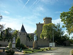 À gauche le monument aux morts, à droite la statue de la Vierge Marie, et en arrière-plan le château.