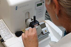 Histologic sample being cut on a microtome. Tissue processing - Microtome is used to cut a ribbon of 5-micron-thick sections from the paraffin block.jpg