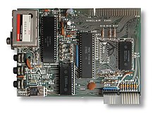 Top-down view of the ZX81 motherboard showing the layout of the components. Four chips are prominent, along with a TV modulator on the top left and a ribbon cable on the bottom right.