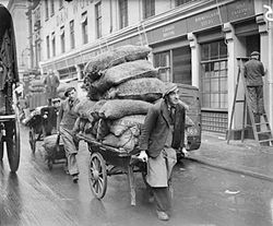 Мужчины перевозят мешки на тележках и тачках 1940 год, Лондон.