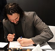 Ривз в Сан-Паулу подписывает книгу левой рукой