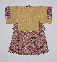 A man's underkimono viewed from the back. It has short sleeves sewn to the body for most of their length. The underkimono is made of a light yellow fabric with fine beige stripes, and the hems and collar are made from two different kinds of arabesque fabric on brick red and darker red.