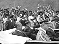 O presidente João Figueiredo e o vice-presidente Aureliano Chaves acenam em direção à população dentro do carro presidencial.