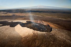 Looking up the slope of Kīlauea, a shield volcano on the island of Hawaiʻi which is the largest and the southeastern-most of the Hawaiian islands. In the foreground, the vent of the volcano has erupted fluid lava to the left. The] crater is at the peak of Kilauea, visible here as a rising vapor column in the background. The peak behind the vapor column is ماونا لوا، a volcano that is separate from Kīlauea.