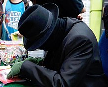 A masked actor representing Russell Lee at a book signing.