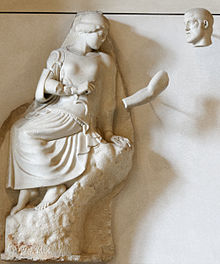 sculpture de marbre : une figure féminine sur un rocher et une tête masculine