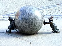 two dwarves pushing a large sphere in opposing directions