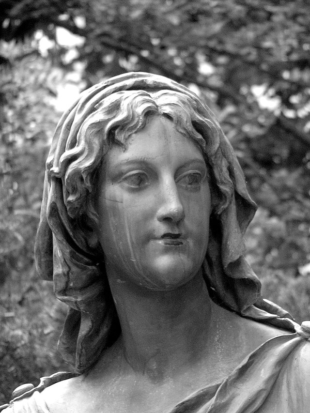A black and white photo of the face of a statue of a woman