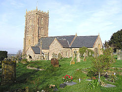 Stone building with square
                tower. In the foreground are gravestones.