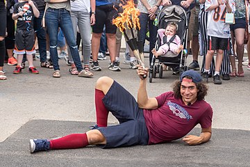 A street performer with sticks that are on fire. The sticks are used for juggling.