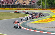 A picture of the 2015 field of formula one cars negotiating the first turns during the 2015 Spanish Grand Prix.