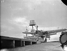 Black and white photograph of a single-engined monoplane running along the deck of an aircraft carrier