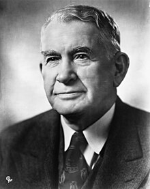 A black and white photo of a man in his fifties wearing a suit