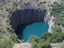 vue d'hélicoptère d'une excavation circulaire taillée dans la roche, remplie d'eau