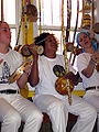 Praticantes de capoeira tocando berimbau