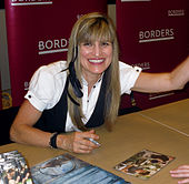 Кэтрин Хардвик улыбается, подписывая DVD.