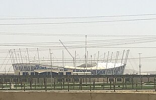 Stade de grandes dimensions en construction dans un paysage semi-désertique.