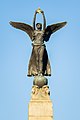 Winged figure holding a golden crown at the top of the obelisk.