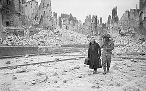 A British soldier escorts an elderly lady in heavily bombed Caen, July 1944 The Allied Campaign in North-west Europe, 6 June 1944 - 7 May 1945 B6794.jpg