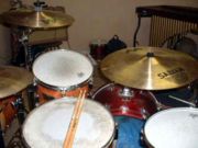 A drum kit from the player's perspective, showing a crash cymbal,  hi-hat, high tom-tom, ride cymbal, snare drum, floor tom-tom and bass drum.