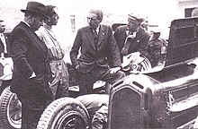 Photo de quatre hommes se tenant derrière une voiture de course dont le capot est ouvert.