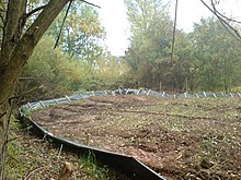 Low plastic fence around an area of recently upturned soil.