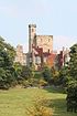 A battlemented house with three towers of different shapes