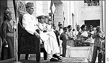 Muhammad Ali Jinnah, seated on the throne of Pakistan, carrying out official duties as the monarch's representative Muhammad Ali Jinnah sitting on the Chair of Governer General wearing a Sherwani.jpg