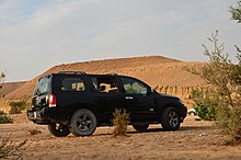 Un Nissan Armada noir devant un paysage désertique.