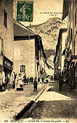 Carte postale ancienne présentant la grande rue et la grande gargouille (au centre de la chaussée).