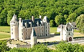 Color aerial photograph of a château with cylindrical towers and a low enclosure protecting it