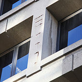 The deteriorating east facade of the J. Edgar Hoover Building, showing where concrete has fallen from the structure. Reinforcing steel rods inside the facade are now rusting. Damaged concrete on east facade - J Edgar Hoover Building - Washington DC - 2012.jpg