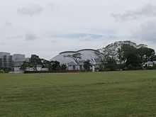 The open field along Geylang Road that the Gay World Amusement Park once stood. The new National Stadium is seen in the background. Gay World Amusement Park.jpg