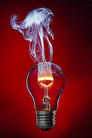 Incandescent lichtbulb wi the tungsten filament smokin an burnin wi a flame due tae the presence o oxygen.