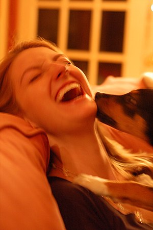 English: Puppy licking a woman's face, while s...