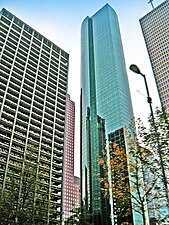 Tall, thin, glass tower with large, rounded outset on one side and strong vertical lines.