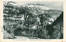 Carte postale en noir et blanc avec des gorges surplombées, en arrière-plan, par une montagne enneigée.