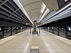 Picture of Macquarie Park station. It consists of an underground platform with platform screen doors and a curved roof.