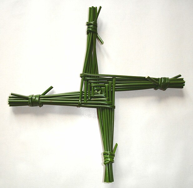 a green cross, woven out of straws, on a white background