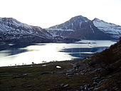 La face sud du Signal du Petit Mont-Cenis, légèrement enneigé, avec un lac au premier plan.