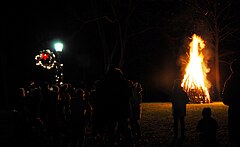 Public bonfire at night, with a holiday wreath on a lamppost
