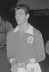 Черно-белое фото мужчины, одетого в футбольную форму ассоциации и держащего плакат.