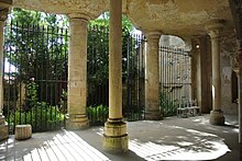 Photographie en couleurs d'une grotte à la large ouverture soutenue par des colonnes.