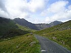 Saint David's Day: Vandrare på väg mot Wales högsta topp Snowdon (1 085 m) i Snowdonia nationalpark i norra Wales. Snowdon ses till höger i bild, med själva toppen precis bakom ett moln.