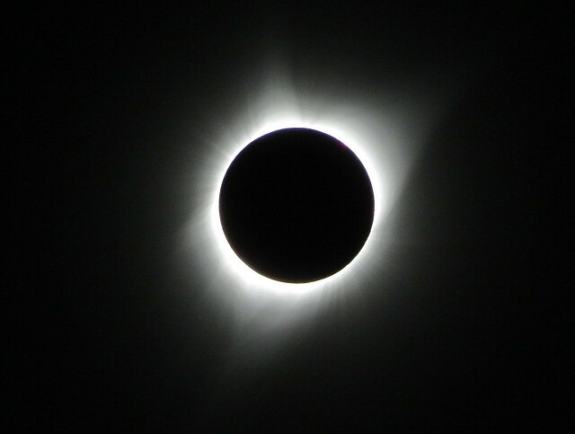 An image of a total solar eclipse at Orin Junction, Wyoming in 2017. A total solar eclipse happens when the Moon completely blocks the face of the Sun.  It is the result of a cosmic coincidence. Even though the Sun is about 400 times bigger than the Moon, it is also about 400 times farther away. This makes the Sun and the Moon appear almost exactly the same size in our sky.